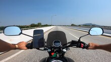 Point Of View Caucasian Man Driving A Yamaha Motorcycle On An Empty Highway In Thailand While Trucks Drive In The Opposite Direction On A Sunny Day With An IPhone Mounted On The Bike.