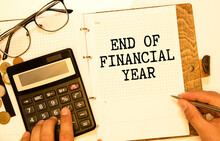 Finance And Economics Concept. The Man Is Holding A Pen And A Notebook With The Inscription - END OF FINANCIAL YEAR.
