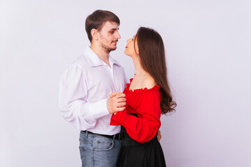 Young couple man and woman hugging on a white background. isolate. A handsome guy in a white shirt hugs a girl with long Spanish-style hair in a red peasant woman blouse and a black corset.