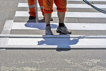 Sticker - Closeup shot of workers' feet during the pedestrian crossing painting in a city street