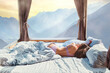 © Goffkein - Beautiful sensual woman dreamer with slim body sleeping on a white soft cozy comfortable bed at window with idyllic calm serene mountains view