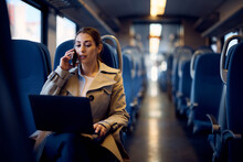 Young Businesswoman Uses Laptop And Talks On The Phone While Commuting To Work By Train.