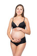Young pregnant woman in black swimsuit. Girl expecting a baby and touching her belly isolated on white background.