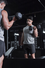 Poster - Making sure his form is on point. Cropped shot of a handsome and athletic young man working out with dumbbells in the gym.