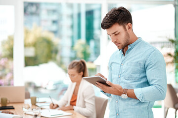 Poster - Taking minutes has never been easier. Cropped shot of a handsome young businessman using his tablet while standing in the boardroom during a meeting.