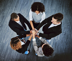 Poster - Teamwork allows for the impossible to take place. High angle shot of a group of businesspeople joining their hands together in a huddle.