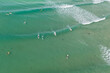 © Austockphoto - Aerial view of a group of surfers catching a wave in the ocean