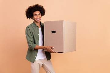 Poster - Portrait of attractive cheerful wavy-haired guy carrying paper box new life isolated over beige pastel color background