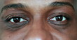 Close-up African American eyes. Man opening eyes and smiling at camera