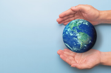 hands holding earth globe on blue background, international human solidarity day concept, world heal