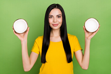 Wall Mural - Portrait of gorgeous satisfied person hold two half coconut isolated on green color background