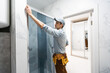 © Angelov - Workers are installing glass door of the shower enclosure.