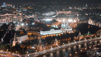 Wall Mural - Close up view from above to Moscow Kremlin at night, beautifully illuminated with evening lights and surrounded by streets with busy traffic, all in motion timelapse.