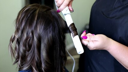 Wall Mural - hairdresser doing a curling iron to a client in a beauty salon