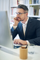 Canvas Print - He has a keen eye for detail. Shot of a mature businessman working at his computer in an office.