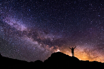 Wall Mural - silhouette of a hiker on the hill in starry night sky. bright milky way galaxy behind him.