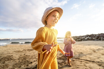 Lovely little sisters having fun at the beach, playing and smiling. Sunset summer time.