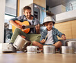 © Lyndon Stratford/peopleimages.com - Its a father-son collaboration. Shot of a happy father accompanying his young son on the guitar while he drums on a set of cooking pots.