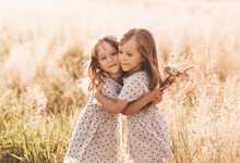 Two Little Happy Identical Twin Girls Playing Together In Nature In Summer. Girls Friendship And Youth Concept. Active Children's Lifestyle.