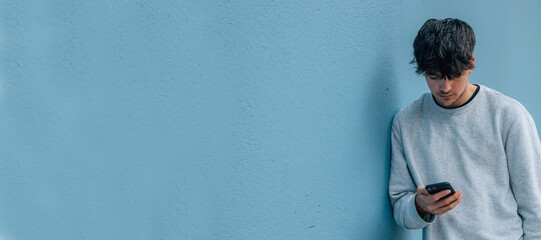 young man with mobile phone on street wall with copy-space