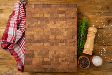 Cutting board, condiments and rosemary on a dark wooden background