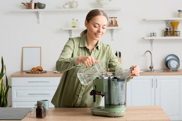 Wall Mural - Young woman pouring water into coffee machine in kitchen