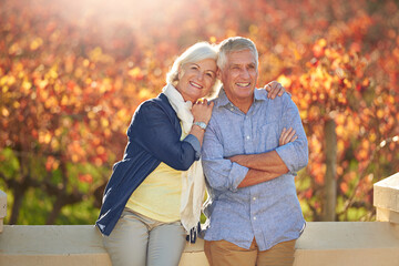 Poster - Enjoying their autumn years. Portrait of a smiling senior couple standing together in front of a vineyard in the autumn.