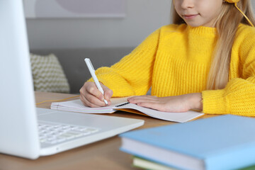 Canvas Print - Cute little girl with modern laptop studying online at home, closeup. E-learning