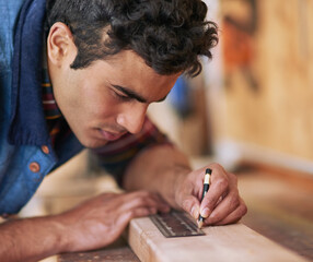 Aufkleber - Getting it right the first time. Shot of a focused handyman measuring a piece of wood while working in his workshop.