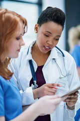 Sticker - Even doctors sometimes need a second opinion. Shot of two young doctors discussing a patients file.