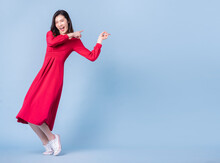 Full Length Image Of Young Asian Woman Wearing Red Dress On Blue Background