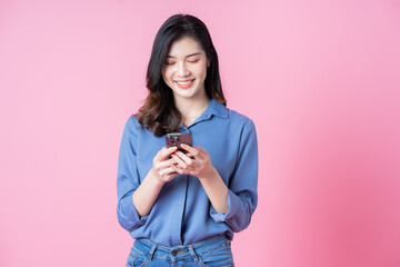 Poster - Image of young Asian business woman using smartphone on pink background