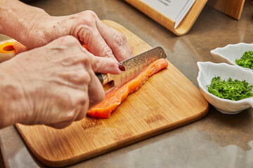 Canvas Print - Chef cuts the salmon with knife into strips to prepare the dish according to the recipe