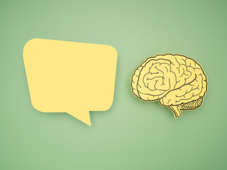 Yellow speech bubble and brain shape made from paper on a green background