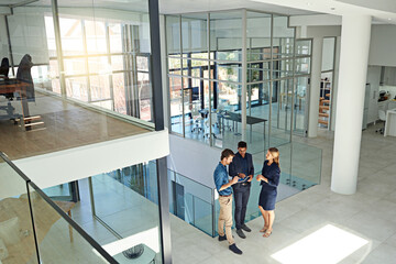 Poster - Contemporary business needs modern thinkers. Shot of three colleagues talking together over a digital tablet while standing in a modern office.