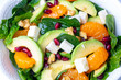 Close up view of spinach, avocado salad with orange, pomegranate and walnut