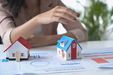 Wall Mural - Small house model on white office desk and real estate agent sitting in background.