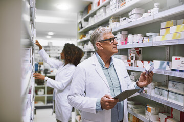 Aufkleber - stocking up. shot of two focused pharmacist walking around and doing stock inside of a pharmacy.
