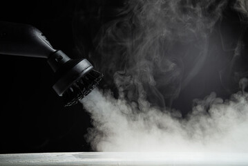 Wall Mural - Disinfection with a steam cleaner. Steam on a black background