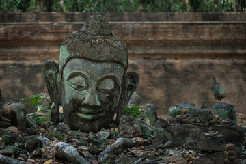 Ancient old ruin Head of Buddha statue carved from sandstone was destroyed and abandoned left in the Wat U Mong Temple.