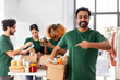 © Syda Productions - charity, donation and volunteering concept - happy smiling male volunteer with food in box and international group of people at distribution or refugee assistance center