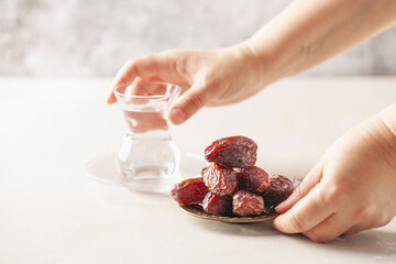 Wall Mural - Glass of water and dry dates on saucer ready to eat for iftar time. Islamic religion and ramadan concept.