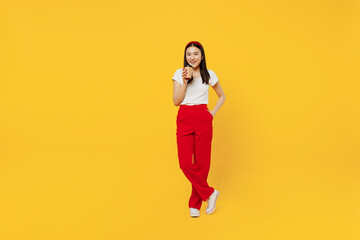 Wall Mural - Full size body length young girl woman of Asian ethnicity 20s years old in casual clothes hold takeaway delivery craft paper brown cup coffee to go isolated on plain yellow background studio portrait.