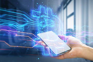 Poster - Close up of female hand holding smartphone with creative blue bitcoin hologram on blurry office interior background. Cryptocurrency and technology concept. Double exposure.