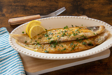 Wall Mural - baked fish with lemon and herbs in dish