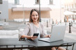 © yurolaitsalbert - young woman is working on a laptop while sitting at a table in an outdoor cafe.