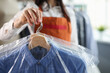 Administrator at dry cleaners keeps clean clothes on hangers in bag