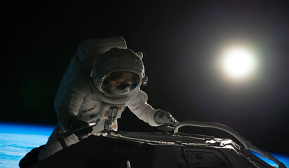 Wall Mural - female astronaut performing spacewalk, working on a outer part of a space craft