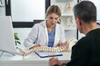 © gpointstudio - Caucasian female doctor talking with patient about his spine