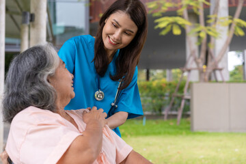 Asian careful caregiver or nurse hold the patient hand and encourage the patient in a wheelchair.  Concept of happy retirement with care from a caregiver and Savings and senior health insurance.